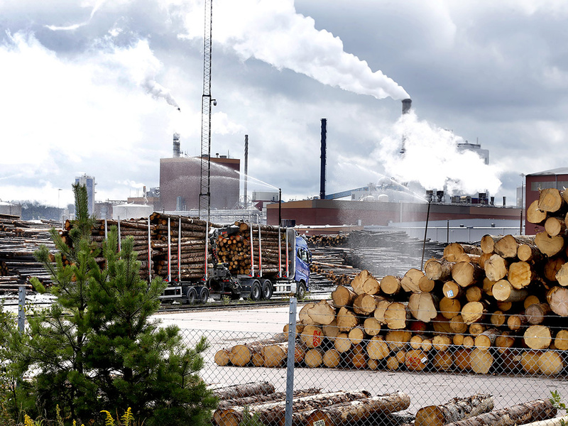 Industrimiljö med timmer, lastbilar och skorstenar